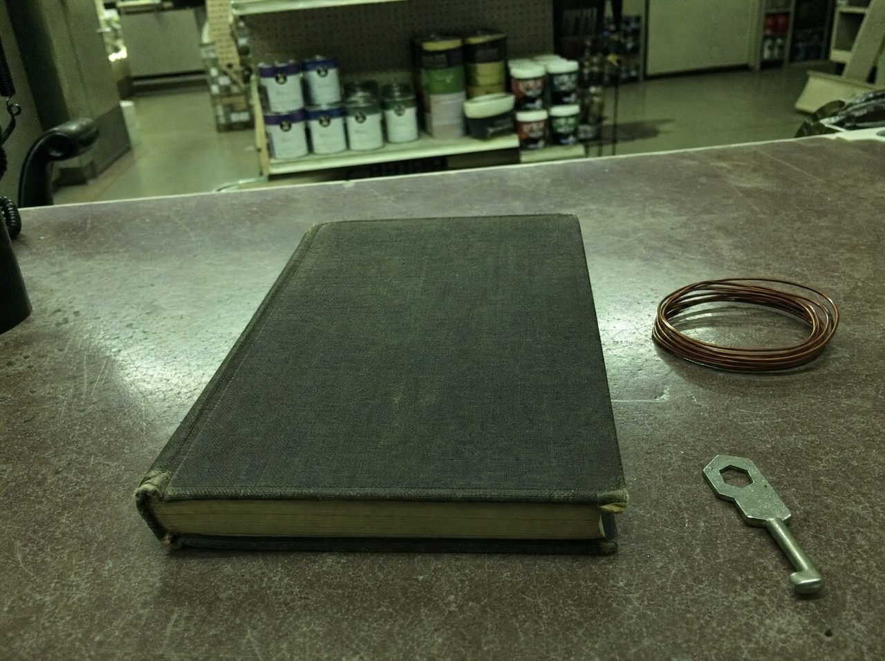 A worn library book left closed on a hardware store service counter under fluorescent light